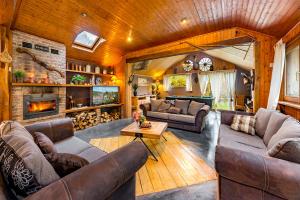 een woonkamer met lederen meubels en een open haard bij cosy holiday home with sauna near river in La-Roche-en-Ardenne