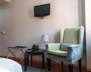 Guest House Douro في بورتو: غرفة بها كرسي وطاولة مع تلفزيون