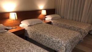 two beds in a hotel room with two lamps at Hotel Select in SantʼIlario dʼEnza