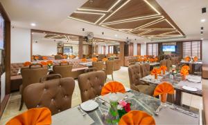 a restaurant with tables and chairs with orange decorations at Lords Eco Inn Morbi in Morbi