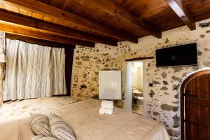 1 dormitorio con 1 cama y TV en la pared en Domus Polymnia, en Spílion