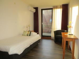 a hotel room with a bed and a chair and a window at Wapen van Exloo in Exloo