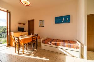 a room with a bed and a table and a bed and a window at Appartamento Bellavista a Fetovaia - Goelba in Fetovaia