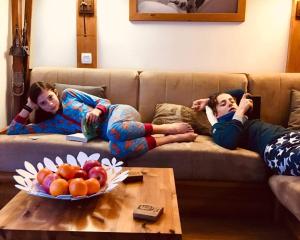 two girls laying on a couch with a bowl of fruit at Luxury Apartment MONTCHAVIN in Montchavin