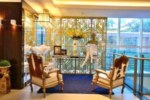 a lobby with two chairs and a wall of windows at Hotel Laghetto Moinhos in Porto Alegre