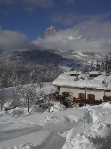 a house covered in snow with a mountain in the background at Baita Fraina in Cortina dʼAmpezzo