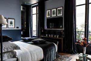 Monsieur George Hotel & Spa - Champs-Elysées في باريس: غرفة نوم بجدران زرقاء وسرير مع الوسائد