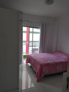 1 dormitorio con 1 cama con colcha roja y ventana en Apartamento no centro - 2, en Balneário Camboriú