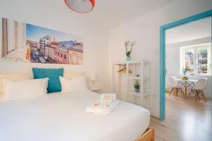 une chambre avec un lit blanc avec un tableau sur le mur dans l'établissement BestVillas Casa do Rio, à Vila Nova de Gaia