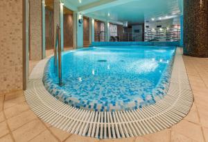 a large swimming pool with blue tiles in a building at Galaxy Hotel in Kraków