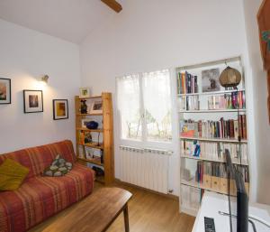 ein Wohnzimmer mit einem Sofa und Bücherregalen in der Unterkunft Gîte Les chênes in Fontenilles