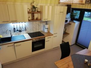 a kitchen with white cabinets and a sink and a table at Berg & See Appartements in Hermagor