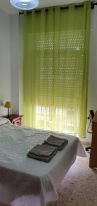 1 dormitorio con 1 cama con cortinas verdes y toallas en Playa La Caleta La Viña Cadiz PLAZA GARAJE GRATIS, en Cádiz