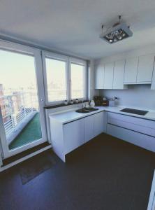 eine Küche mit weißen Schränken und einem großen Fenster in der Unterkunft Penthouse met groot terras Oostende in Ostende