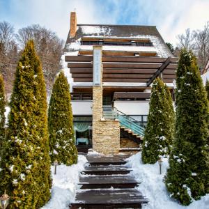 a building in the snow with trees in front at Casa Freya in Buşteni