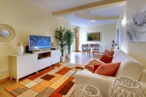 a living room with a white couch and a tv at Marina Ocean Residence in Albufeira