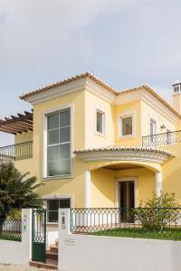 ein gelbes Haus mit einem Zaun davor in der Unterkunft Laguna Formosa - Holidays in Algarve in Faro