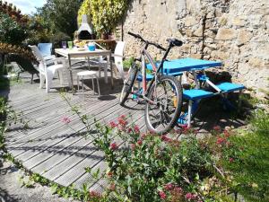 una bicicletta parcheggiata su una terrazza in legno con tavolo e sedie di GUEST HOUSE groupe et Famille a Saint-Paimboeuf