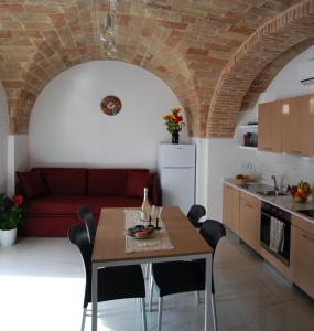 a kitchen and living room with a table and a red couch at Residence Borgo Offida in Offida
