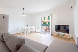 Sala de estar blanca con sofá y TV en Edificio Príncipe en Colonia Sant Jordi