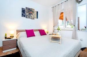 una camera da letto con un grande letto bianco con cuscini rosa di F&R Apartments a Rovigno (Rovinj)