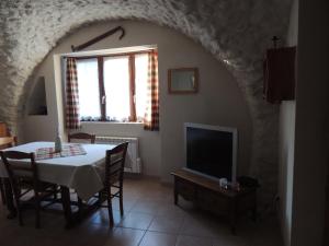 a dining room with a table and a tv at Les grands bois in Gap