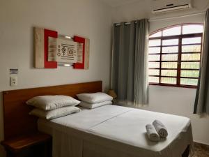 Un dormitorio con una cama con almohadas blancas y una ventana en Pousada Pollyana, en Pirenópolis 49 fotos más