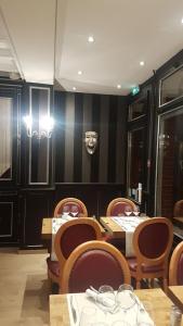 a dining room with tables and chairs and a wall at Hôtel La Champagne Ardenne Cabourg in Cabourg