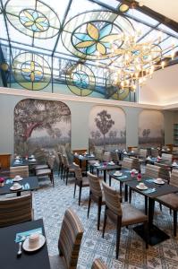 una sala da pranzo con tavoli, sedie e soffitto in vetro colorato di Hôtel Saint-Pétersbourg Opéra & Spa a Parigi