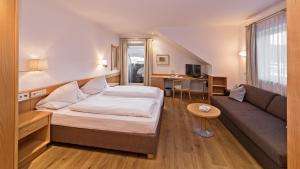 una camera d'albergo con un letto e un divano di Hotel Post - OlangCard included a Valdaora Altre 37 foto