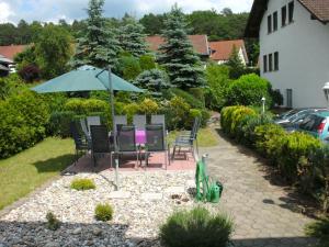 een patio met een tafel en stoelen en een parasol bij Hotel Tannenhof in Erlenbach am Main
