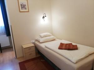 Habitación pequeña con cama y mesita de noche en Polus Pension, en Sopron