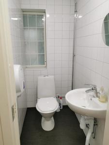 La salle de bains blanche est pourvue de toilettes et d'un lavabo. dans l'établissement IzKaMaGe Hotel, à Västerås