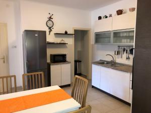 eine Küche mit einem Kühlschrank und einem Tisch mit Stühlen in der Unterkunft Apartments Mikelic in Rab