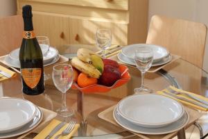 un tavolo di vetro con un cesto di frutta e una bottiglia di vino di Residence Geranio a Domaso