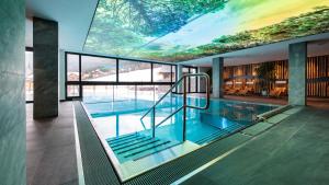 a swimming pool in a building with a large ceiling at ALMGUT - Mountain Wellness Hotel in Sankt Margarethen im Lungau