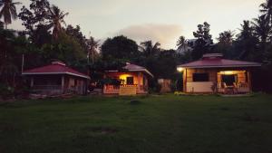 a house with lights on in a field at Paco's Garden Home Stay in Mambajao