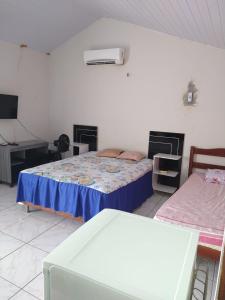 a bedroom with two beds and a desk in it at Casa de Dona Diana in Barreirinhas