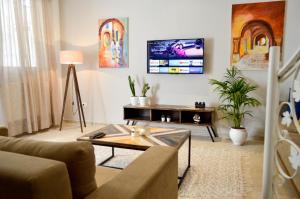 - un salon avec un canapé et une télévision murale dans l'établissement Cosy Triplex in La Marsa - 3 bed 2 Bath, à La Marsa