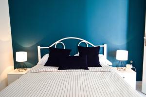 a blue bedroom with a white bed with black pillows at Cosy Triplex in La Marsa - 3 bed 2 Bath in La Marsa