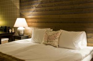 ein Bett mit weißen Kissen und einem Kopfteil aus Holz in der Unterkunft Jennys Hotell och Restaurang in Arvika