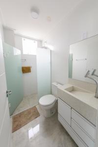 a white bathroom with a toilet and a sink at Vila Beach Residence in Pinheira