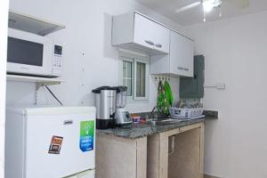 La cuisine est équipée de placards blancs et d'un réfrigérateur blanc. dans l'établissement Hostal Familiar Carmencita, à Panama City