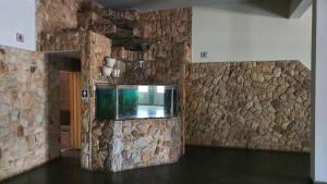 a room with a stone wall with a fish tank at Delta Hotel in Andradina