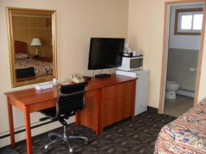 a hotel room with a desk with a computer and a television at Forest Plaza Motel in Mount Forest