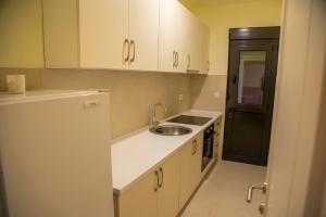 a kitchen with white cabinets and a sink and a refrigerator at Apartments E&S in Ulcinj
