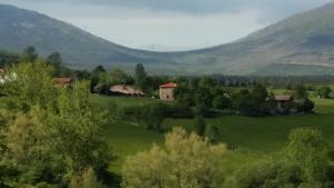 Centro Jardín Mandala في Valberzoso: قرية صغيرة في حقل أخضر مع جبال في الخلفية