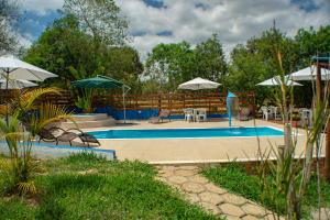 a pool with tables and chairs and umbrellas at João e Maria Restaurante e Chalés in Tiradentes