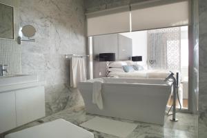 a white bathroom with a tub and a bed at Royal Thalassa Monastir in Monastir
