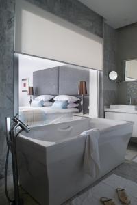 a bathroom with a bath tub in front of a bed at Royal Thalassa Monastir in Monastir